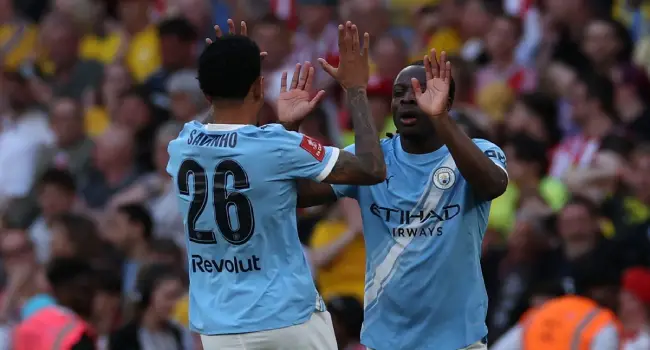 Manchester City’s Belgian midfielder #11 Jeremy Doku (R) celebrates with Manchester City’s Brazilian midfielder #26 Savinho (L) after scoring their first goal during the English FA Cup semi final football match between Manchester City and Southampton at Wembley stadium in London, on April 25, 2026. (Photo by Adrian Dennis / AFP)