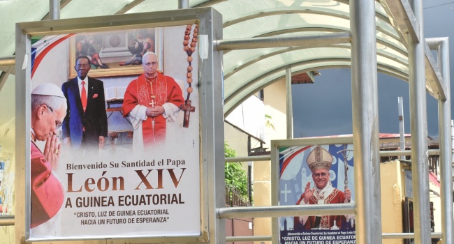 A general view of a billboard displaying a portrait of Pope Leo XIV (L and R) and Guinea Equatorial President, Teodoro Obiang (C), in Malabo on April 15, 2026 ahead of the Pope’s visit to Equatorial Guinea. (Photo by Samuel Obiang / AFP)