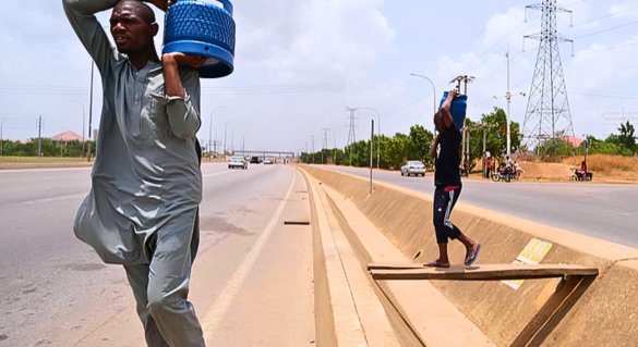 Residents carry cooking gas cylinders along the Airport Road in Abuja on April 18, 2020.